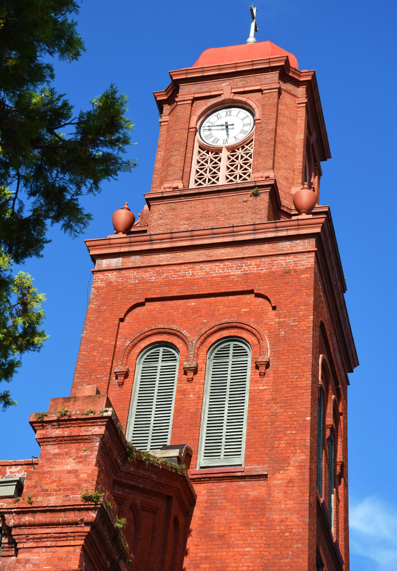 The full red-brick façade and clock tower of Blessed Francis Xavier Seelos Church rising against a deep blue New Orleans sky